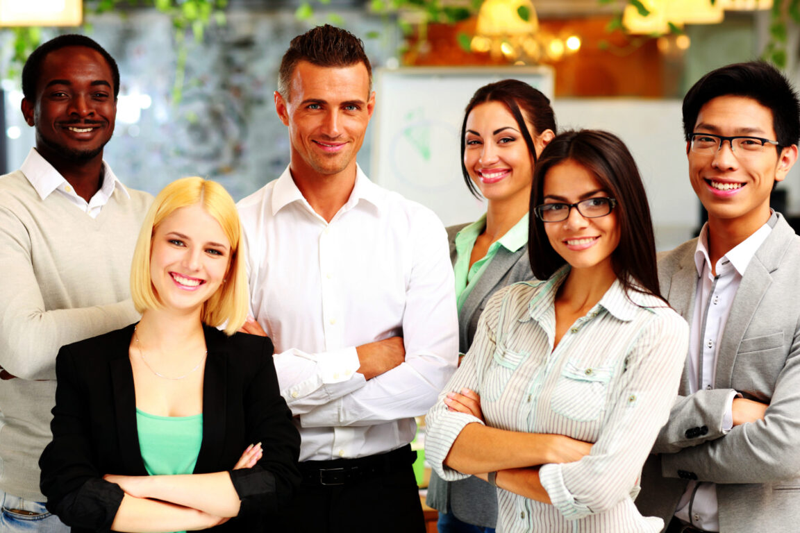 happy-group-of-co-workers-standing-in-office-scaled-1152x768